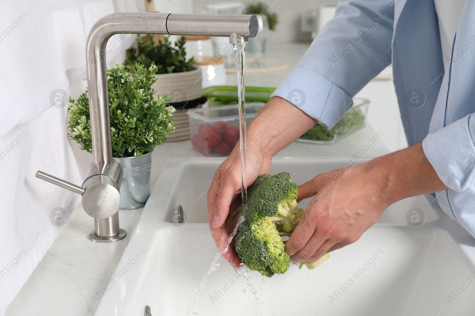 Photo of Man washing fresh broccoli in kitchen, closeup. Food storage