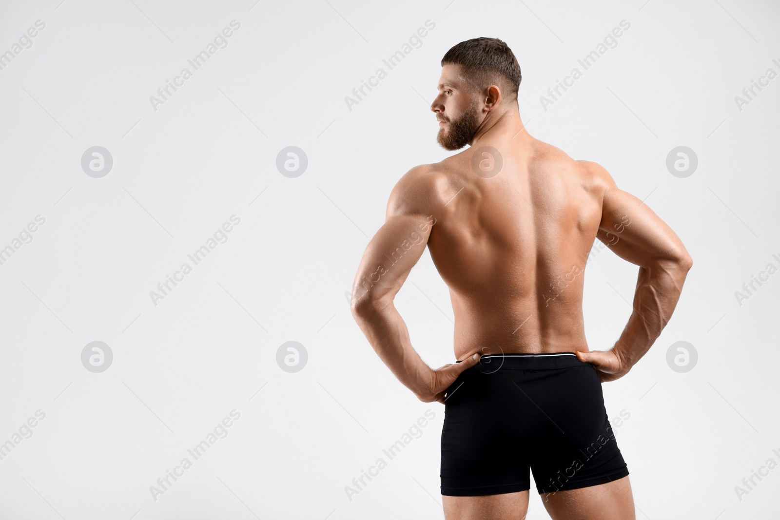 Photo of Young man is stylish black underwear on light grey background, back view. Space for text