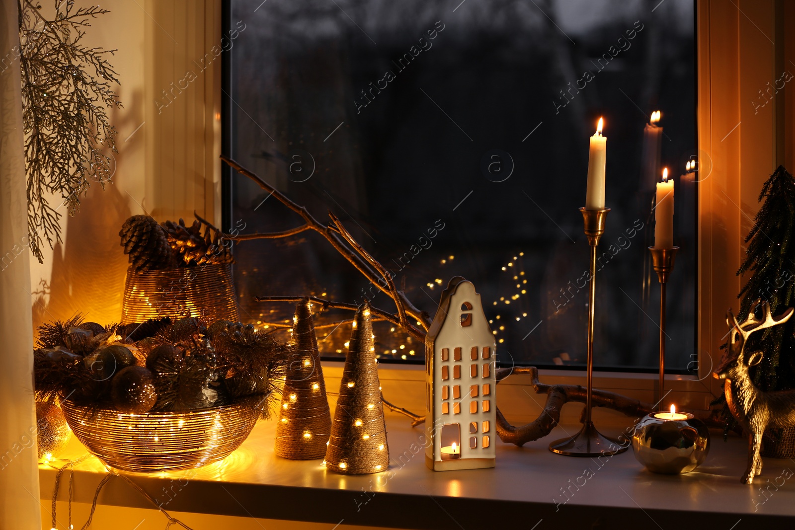 Photo of Many beautiful Christmas decorations, candlesticks and festive lights on window sill indoors