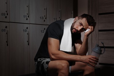 Handsome tired man with shaker in locker room