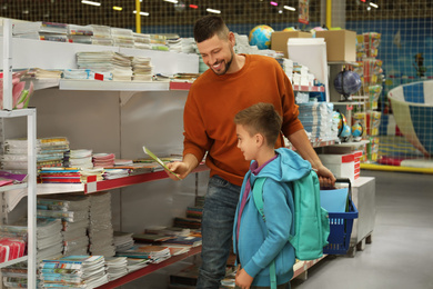 Little boy and father choosing school stationery in store