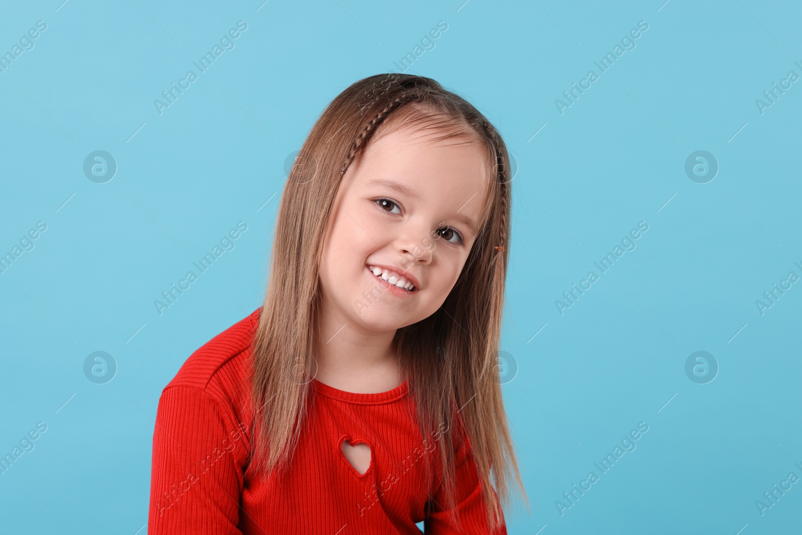 Photo of Portrait of happy little girl on light blue background