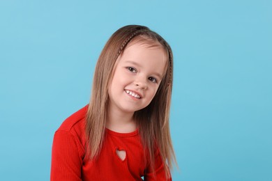 Photo of Portrait of happy little girl on light blue background