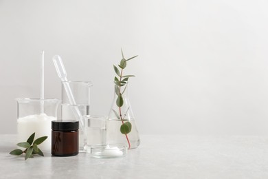 Natural ingredients for cosmetic products and laboratory glassware on white table