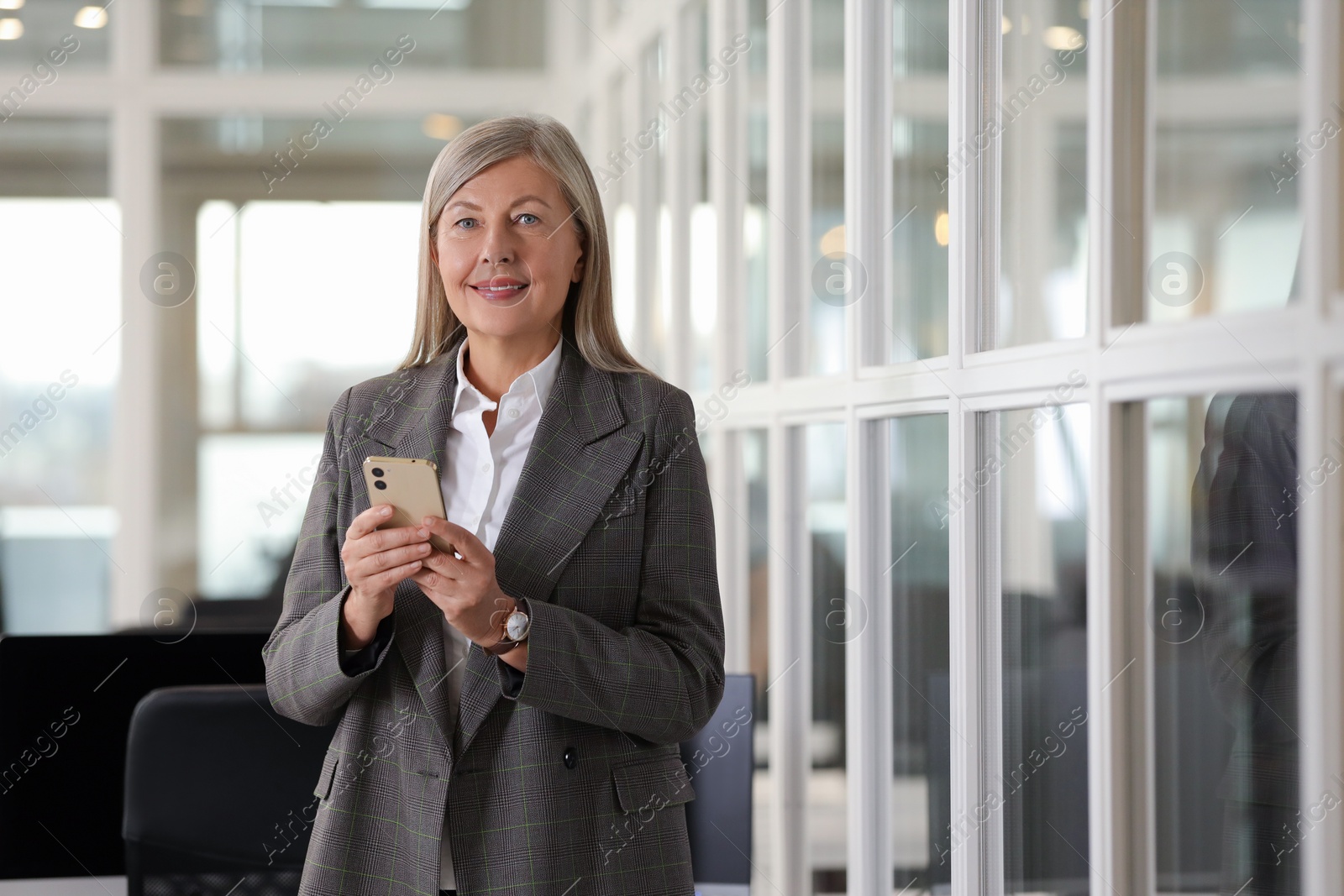 Photo of Smiling woman with smartphone in office, space for text. Lawyer, businesswoman, accountant or manager