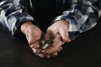 Poor elderly man holding coins in hands at table, closeup