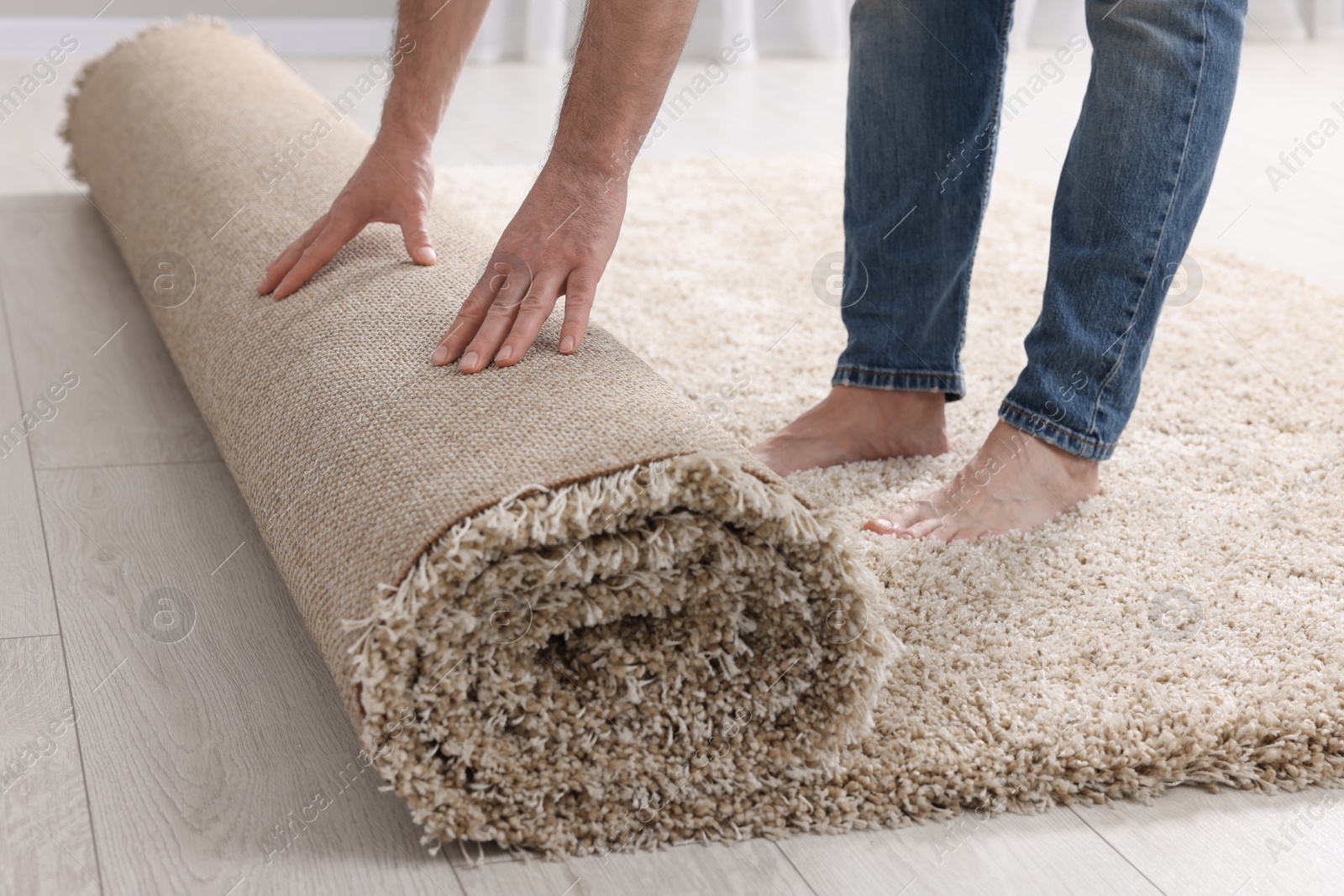 Photo of Man unrolling carpet on floor in room, closeup