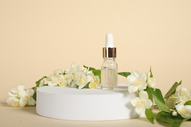 Presentation of essential oil in bottle and beautiful jasmine flowers against beige background