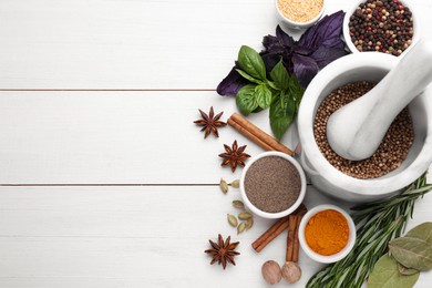 Photo of Mortar with pestle and different spices on white wooden table, flat lay. Space for text