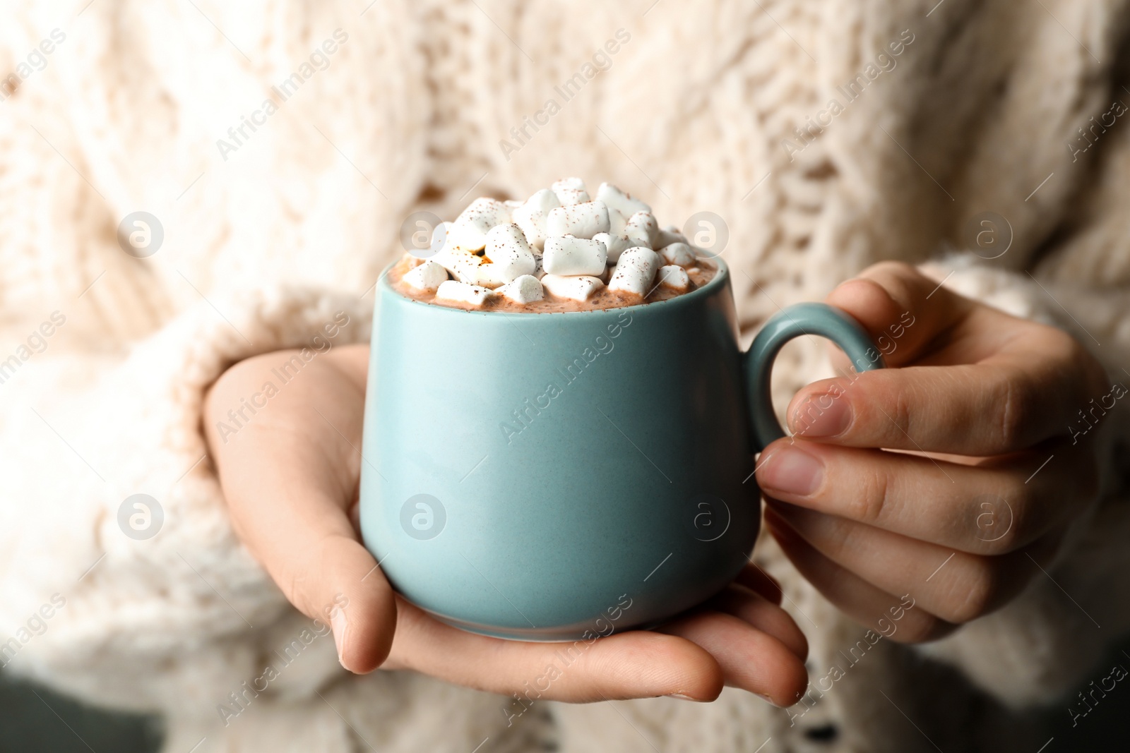 Photo of Woman holding cup of aromatic cocoa with marshmallows, closeup