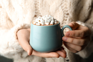 Photo of Woman holding cup of aromatic cocoa with marshmallows, closeup