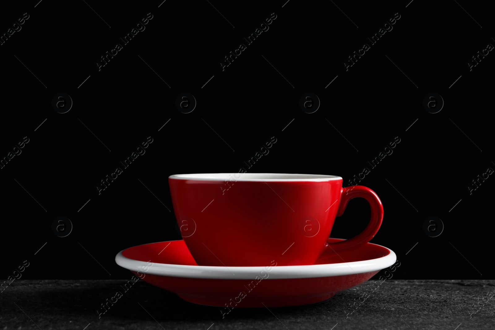 Photo of Red cup with aromatic coffee on black textured table