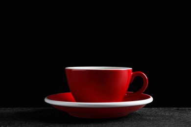 Red cup with aromatic coffee on black textured table