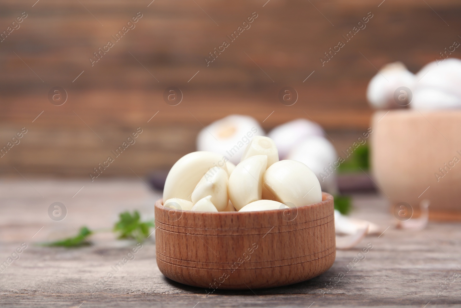 Photo of Wooden bowl with ripe garlic cloves on table