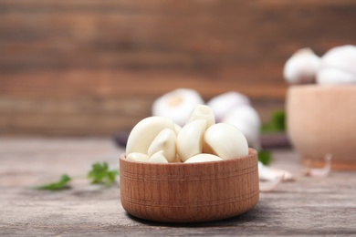 Photo of Wooden bowl with ripe garlic cloves on table