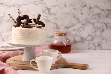 Delicious cake decorated with sweets served on white wooden table, space for text