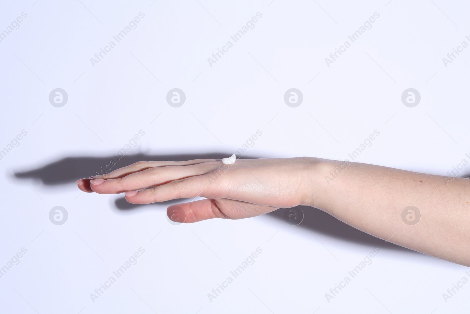 Photo of Woman with cream on her hand against white background, closeup