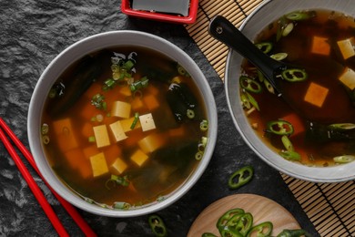 Delicious miso soup with tofu served on black textured table, flat lay