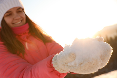 Photo of Woman holding pile of snow outdoors. Winter vacation