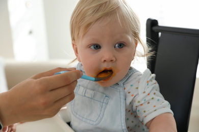 Mother feeding her cute little baby with healthy food at home