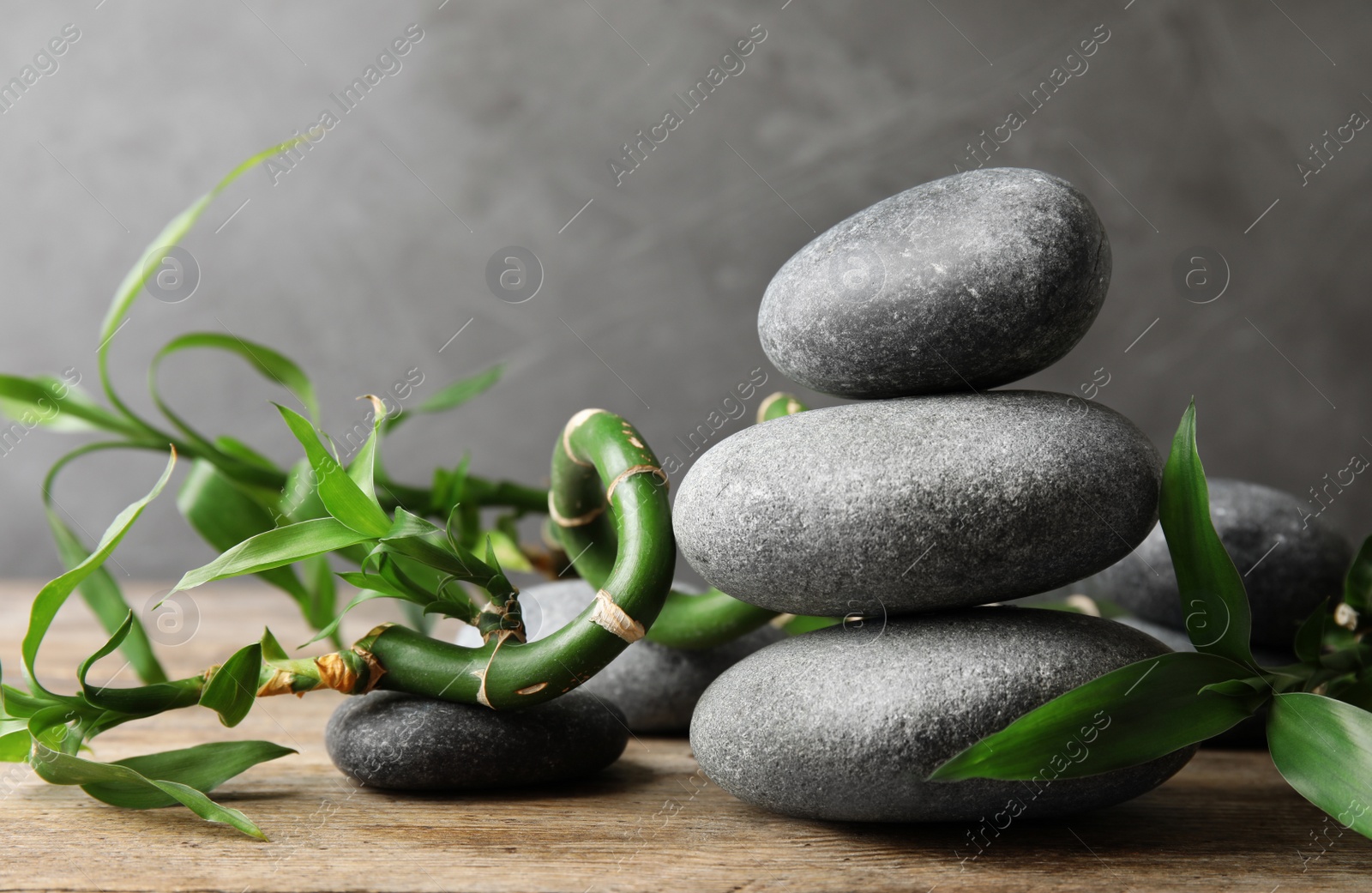 Photo of Stacked zen stones and bamboo on table against grey background. Space for text