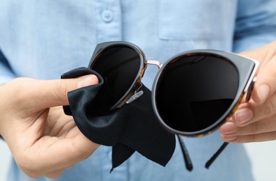 Woman wiping sunglasses with microfiber cleaning cloth, closeup