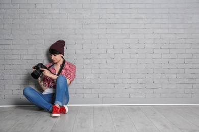 Photo of Young female photographer with camera near brick wall