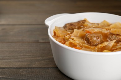 Photo of Tasty cabbage soup with meat and carrot on wooden table, closeup. Space for text