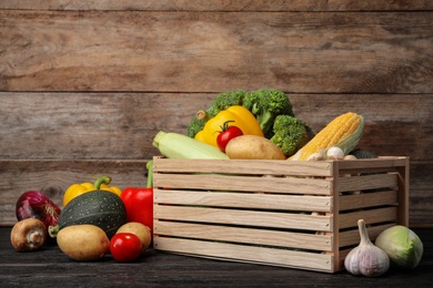 Photo of Different fresh vegetables and crate on wooden table