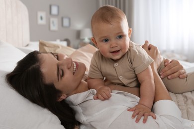 Happy young mother with her cute baby on bed at home