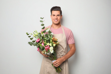 Photo of Florist with beautiful bouquet on light background