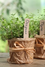 Photo of Aromatic potted oregano and thyme on wooden table, closeup