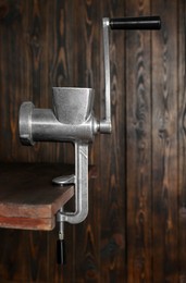 Metal manual meat grinder on table against wooden background