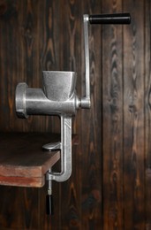 Photo of Metal manual meat grinder on table against wooden background