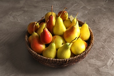 Photo of Wicker bowl with ripe pears on grey background