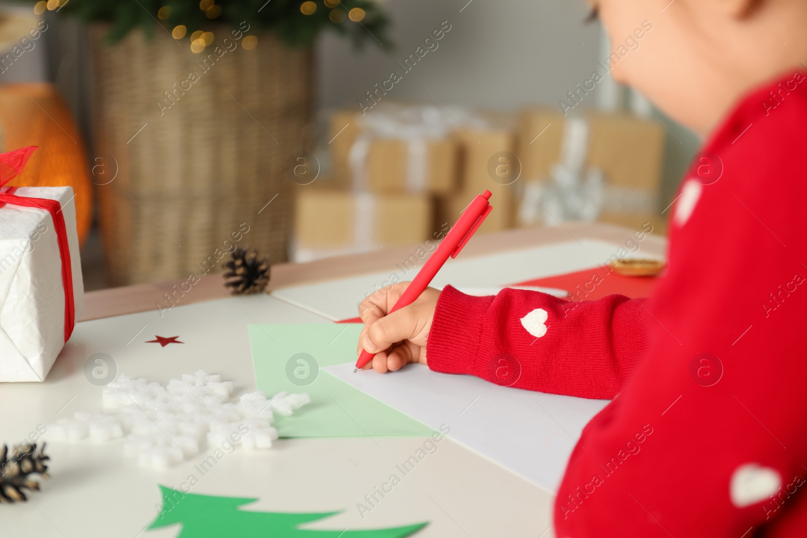 Photo of Cute child writing letter to Santa Claus at table, closeup. Christmas tradition