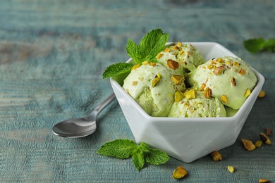 Photo of Delicious pistachio ice cream on blue wooden table. Space for text