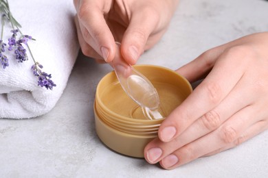 Woman using under eye patches at light table, closeup. Cosmetic product