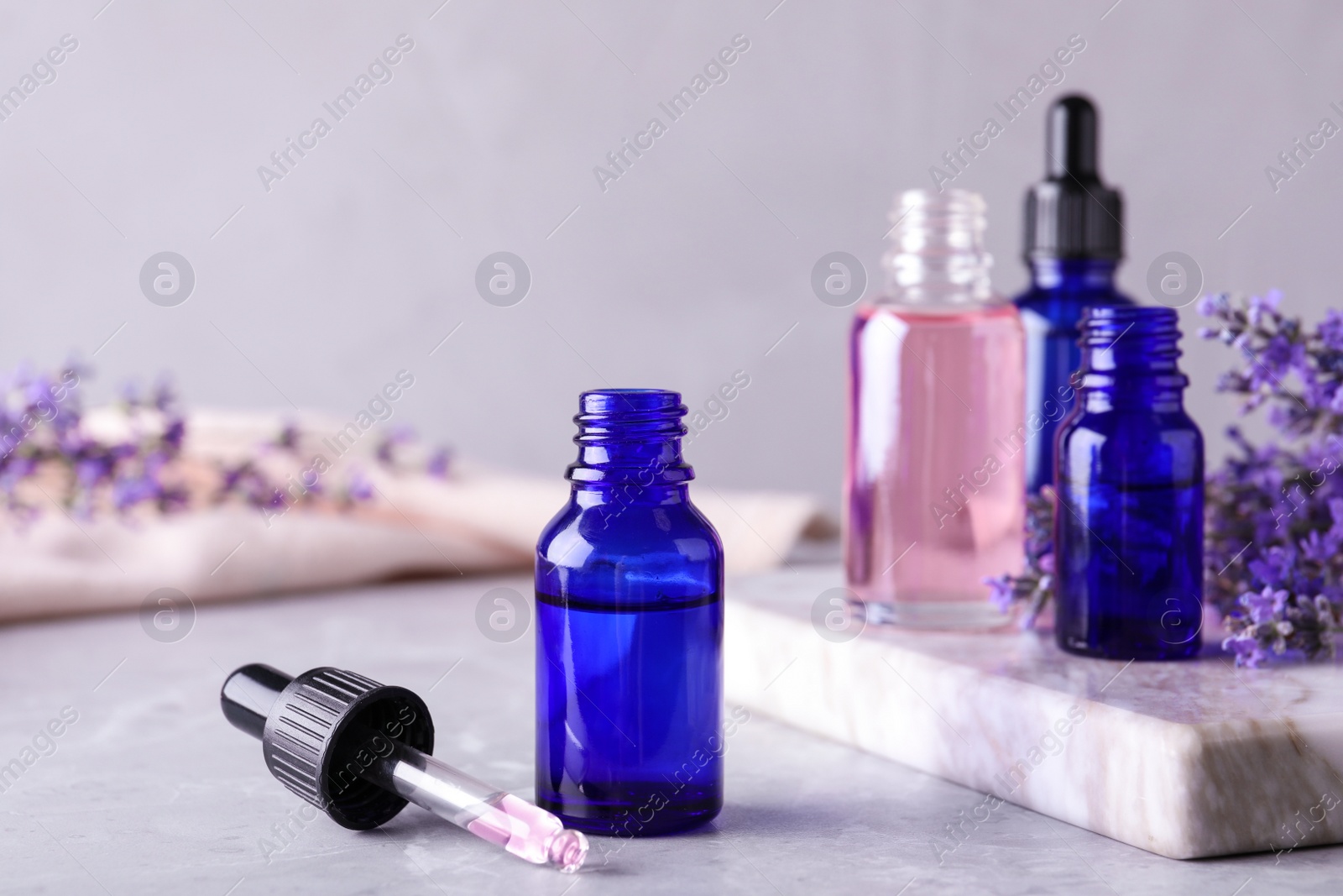 Photo of Bottles of lavender essential oil on marble table