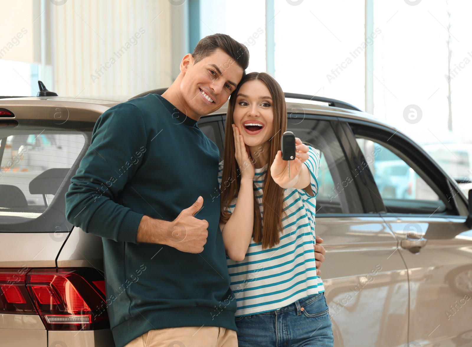 Photo of Happy couple with car key in modern auto dealership