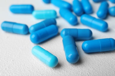 Photo of Many blue pills on light surface, closeup