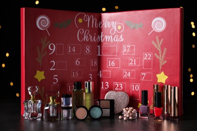 Photo of Christmas advent calendar with perfumes and makeup products on table