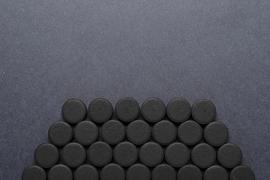 Photo of Activated charcoal pills on grey background, flat lay with space for text. Potent sorbent