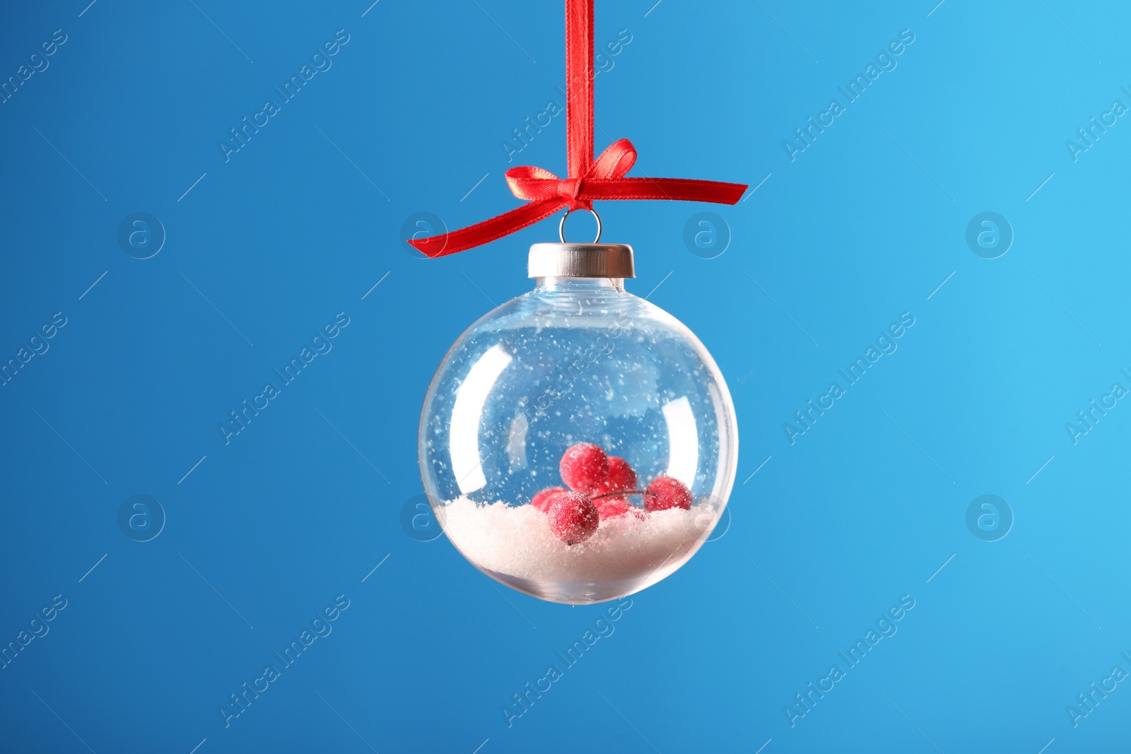 Photo of Decorative snow globe hanging on light blue background