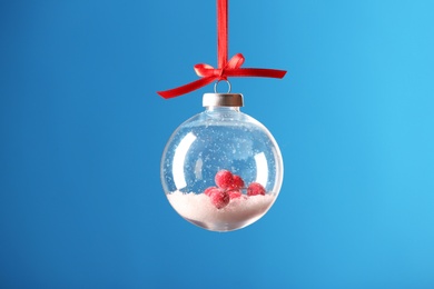 Photo of Decorative snow globe hanging on light blue background