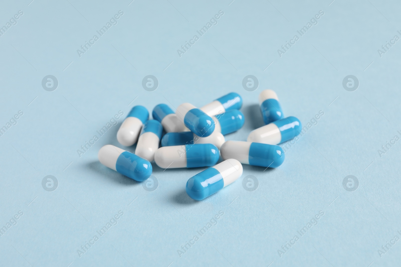Photo of Pile of pills on light blue background, closeup