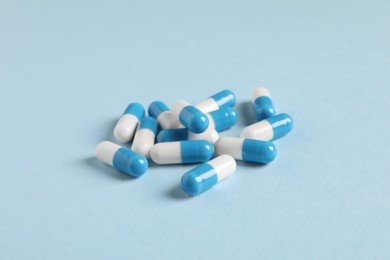 Pile of pills on light blue background, closeup