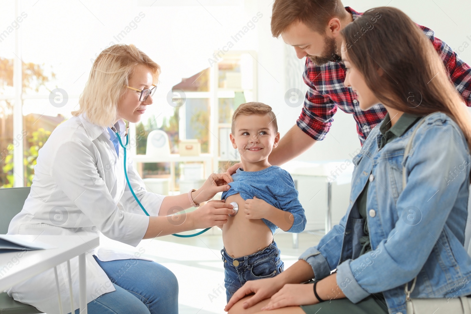 Photo of Children's doctor examining little boy with stethoscope in hospital