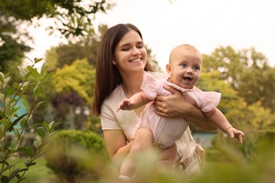 Happy mother with adorable baby walking in park on sunny day