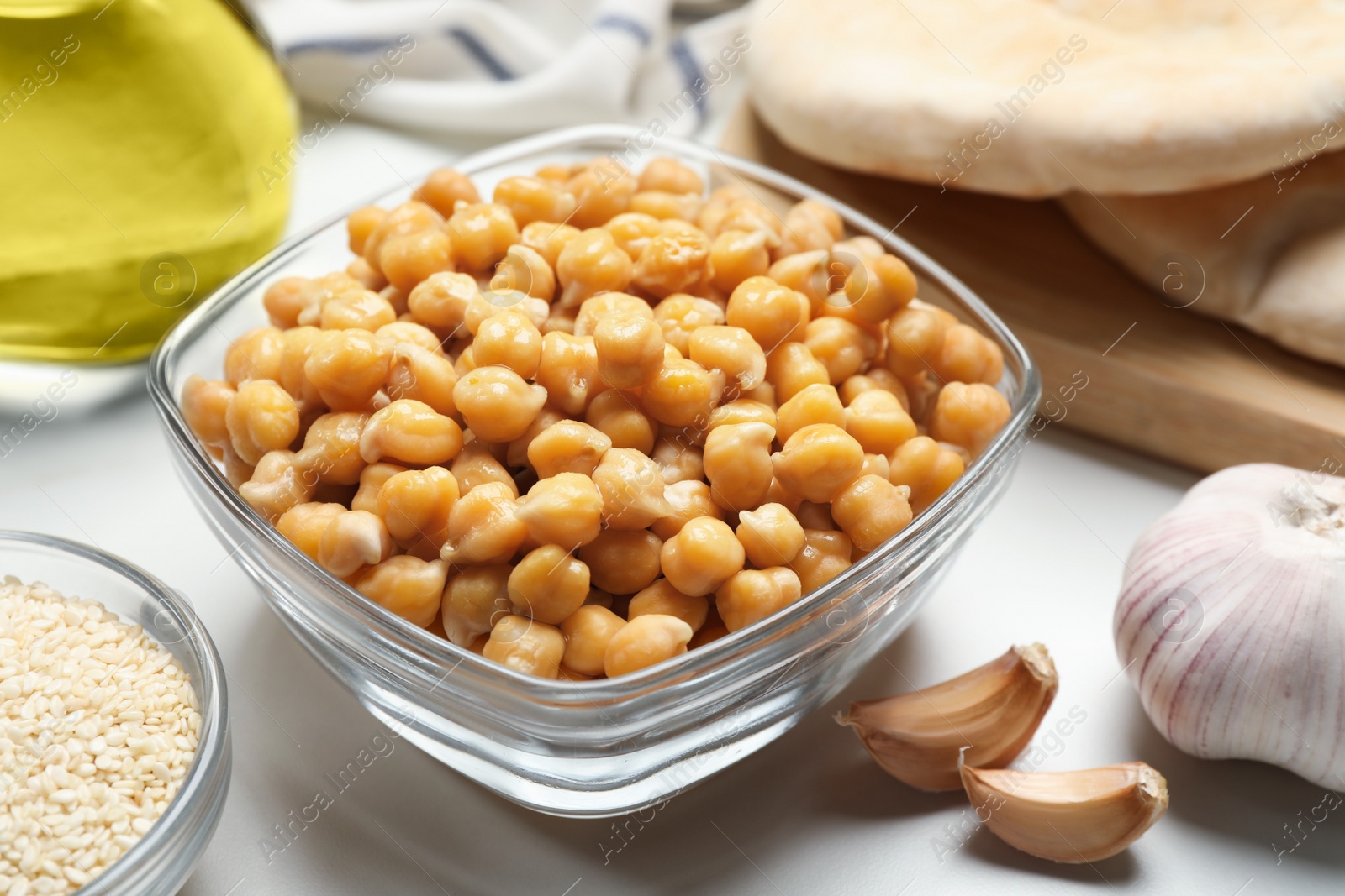 Photo of Delicious chickpeas and different products on white table. Hummus ingredients